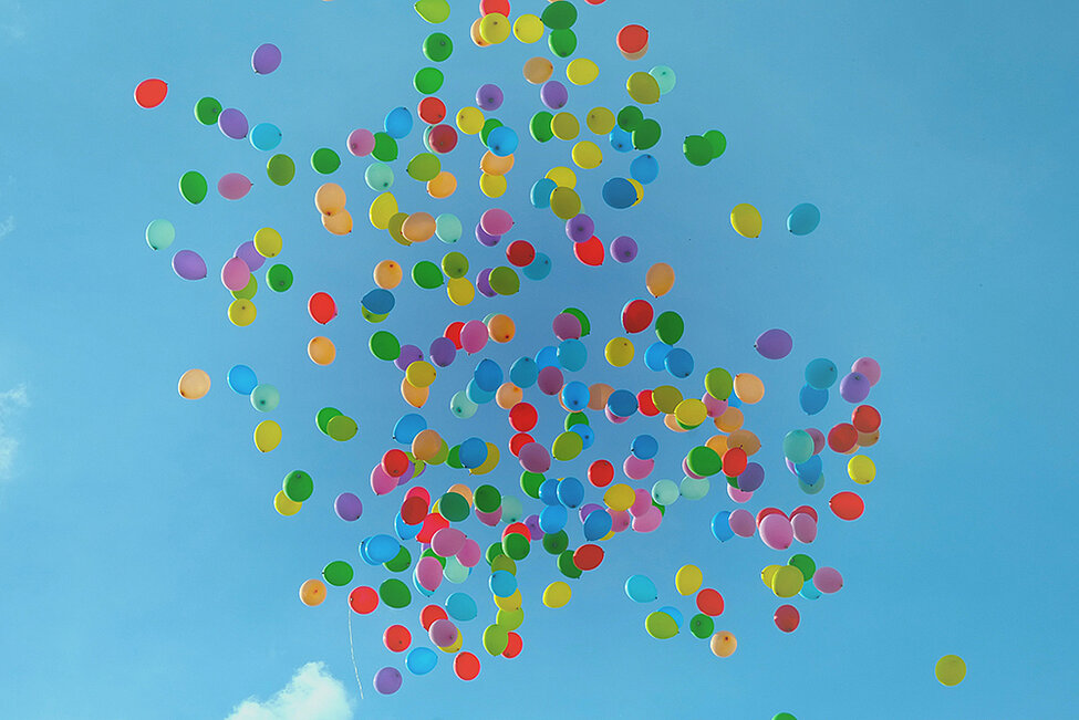 Många ballonger i olika färger flyger fritt på himlen. Foto.