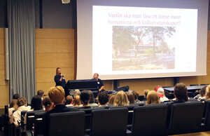 Gabriella Nilsson står längst fram och pratar inför studenterna i aulan. Foto.