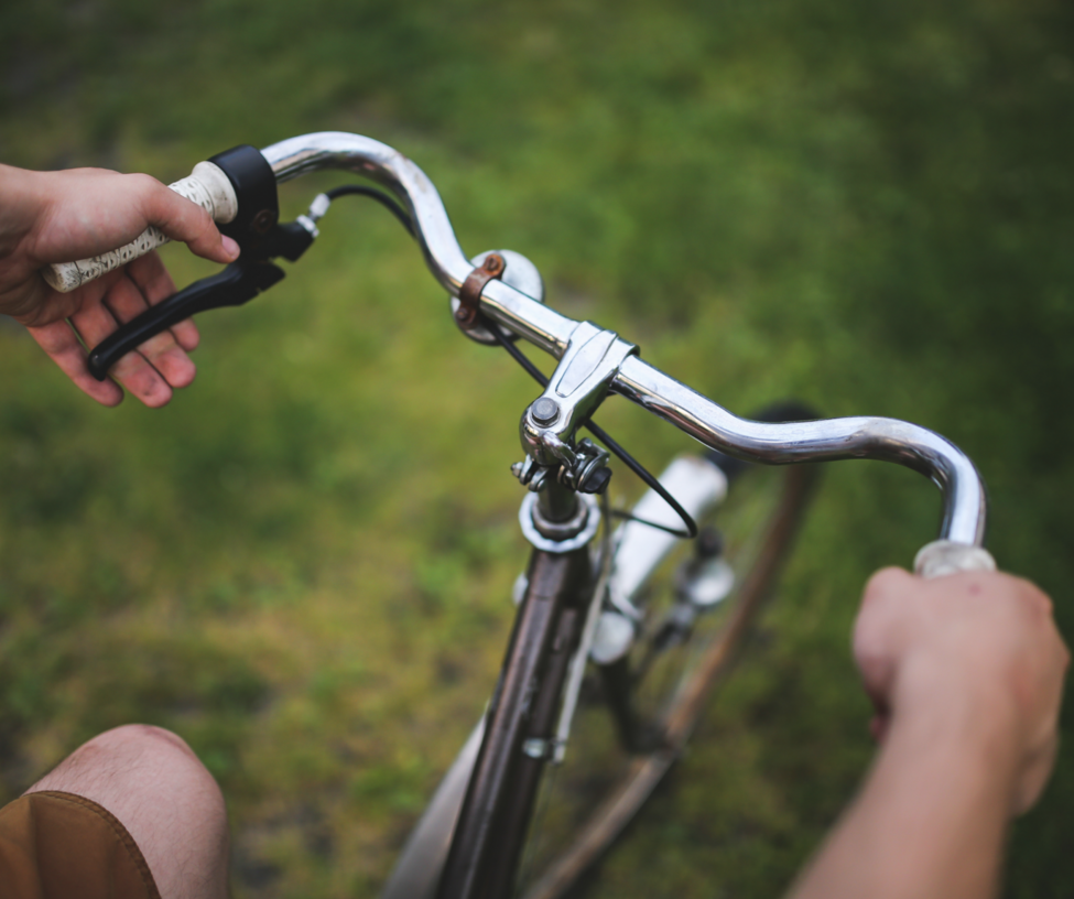 Två händer som håller i ett cykelstyre.